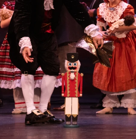 Nutcracker toy soldier character with young dancer on stage
